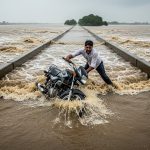 Riding bike on overflowing bridge proved costly: Man trying to be a hero's life endangered, bike swept away!